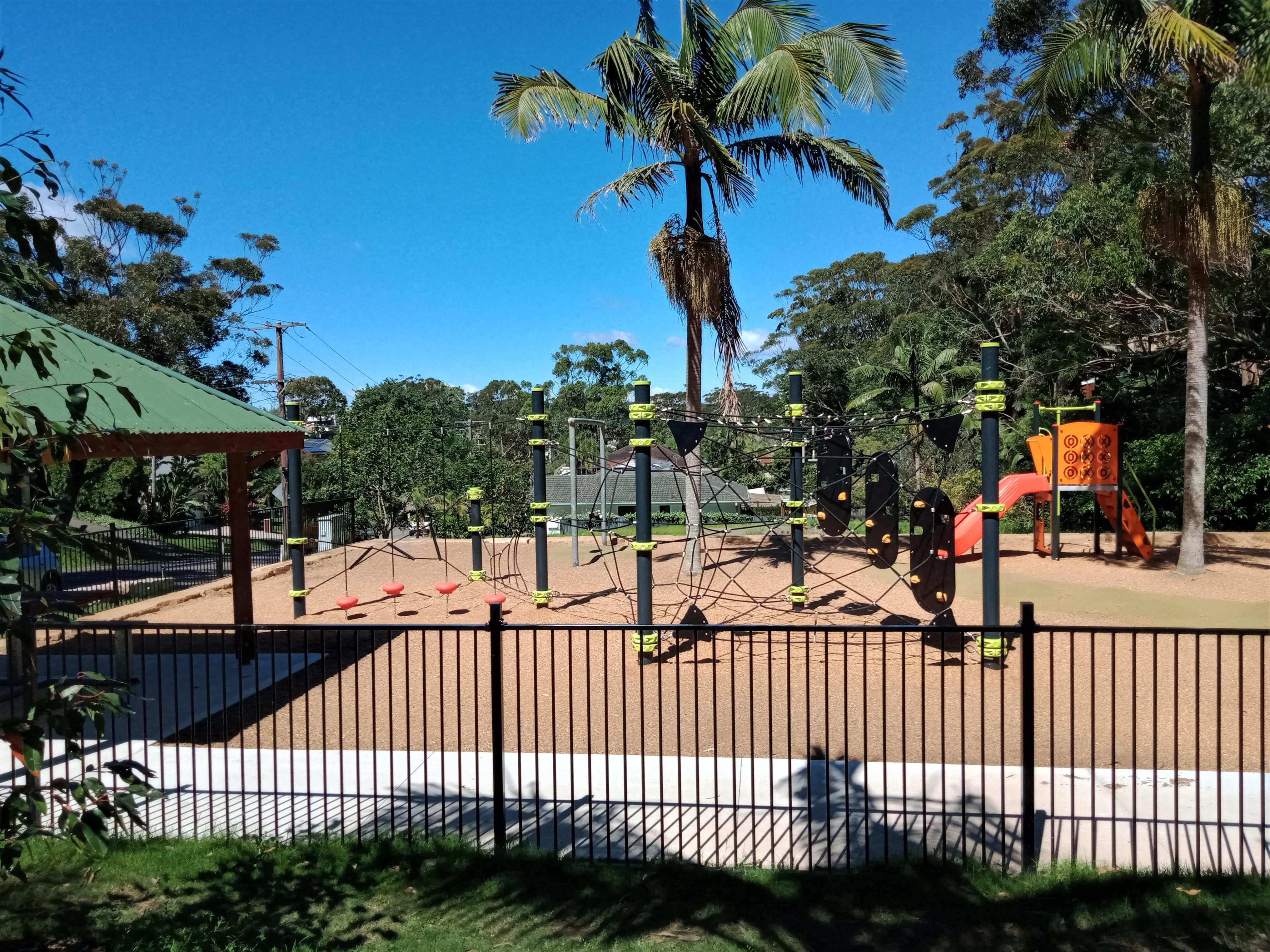 Playground under a Palm Tree with fence and shelter with table