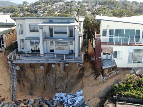 Coastal beach house dangling over sand dunes