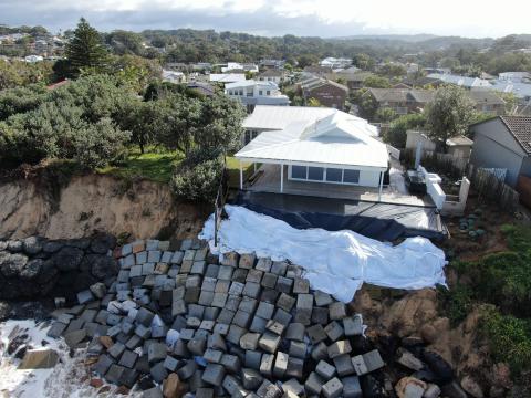 Concrete blocks stacked on the beach near a house