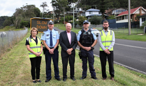 Council staff with police on a local road with a slow down sign in background 