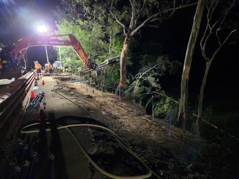 Construction workers using heavy machinery at night with Hawkesbury River in background