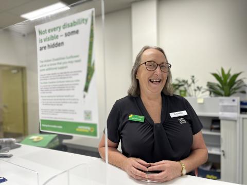 Council Customer Service Officer working at front desk wearing Hidden Disability Sunflower merchandise