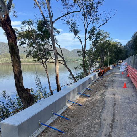 Construction workers stabilising the embankment along Wisemans Ferry Road with Hawkesbury River in background 